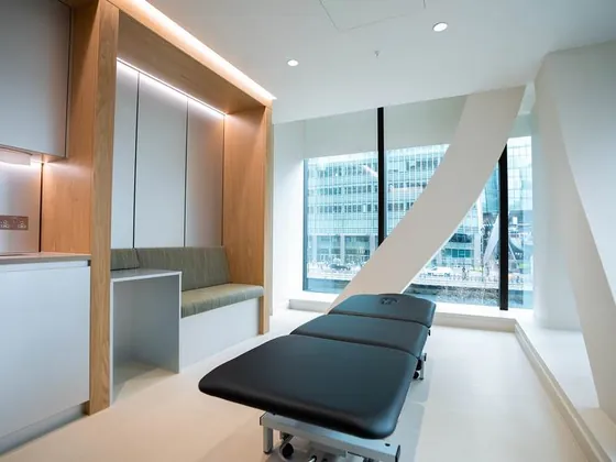 A treatment room at UNTIL Canary Wharf with a couch beside a full height window.