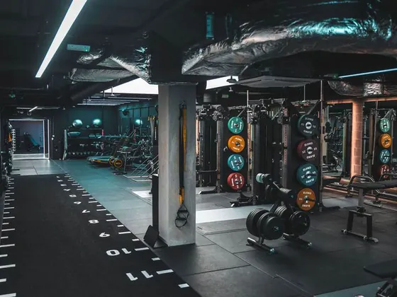 The gym floor at UNTIL Soho, lit low with racks along both walls.
